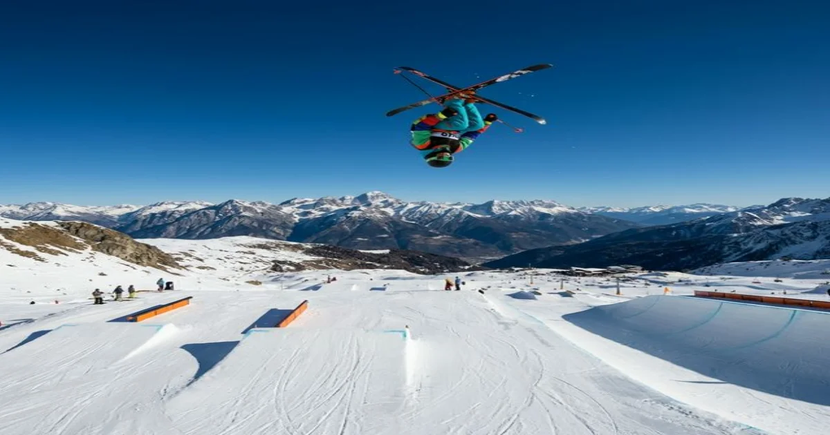 Atleta freestyle in volo sullo snow park di Livigno con le Alpi sullo sfondo